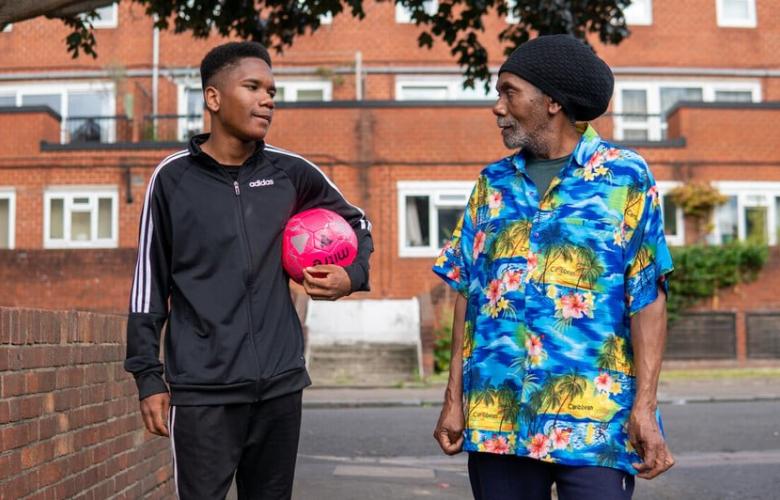 Man and boy with a football walking down the street