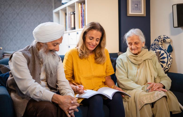 Three older adults smiling together indoors looking at a document