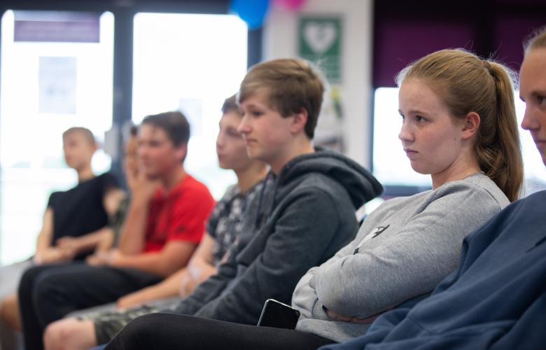 Children sat in chairs in a line.