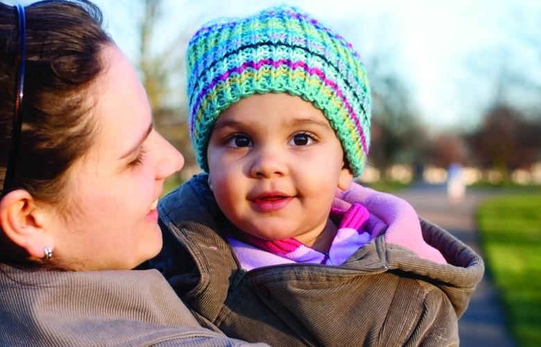 A baby being held by an adult in a park setting.