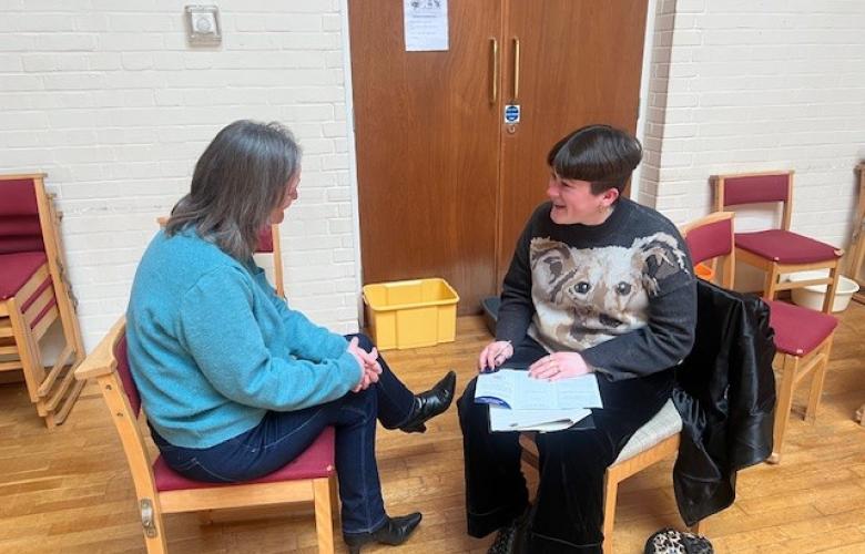 Two women talking while sat down.