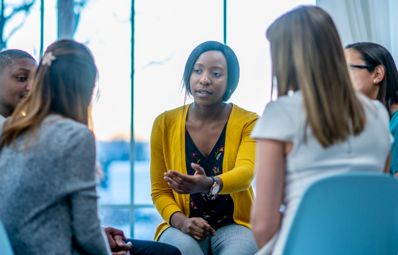 A group discussion with several people sat in chairs indoors. 