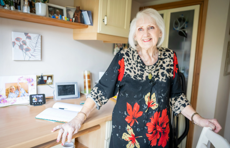 An older woman in a kitchen smiling.