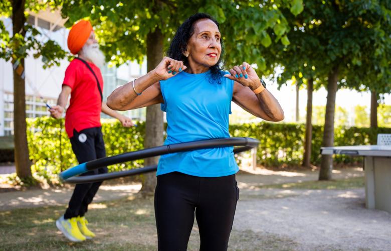 Two people exercising outside with a skipping rope and hoola hoop