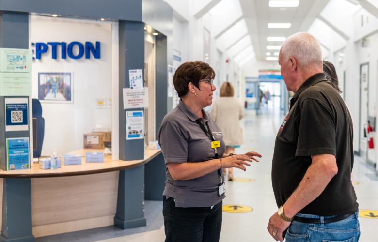 A volunteer talking to a man in a hospital corridor.