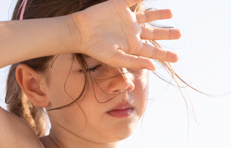 A child shielding their eyes in the sun.