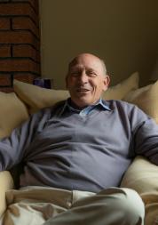 Portrait of an older man sat on the sofa.
