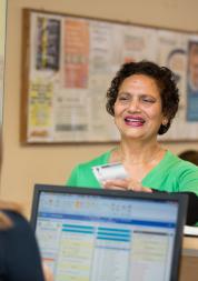Woman talking at a GP reception counter.