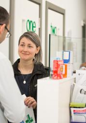 A woman at a pharmacy counter smiling.