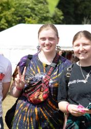 Three young people outside in a sunny, festival environment.