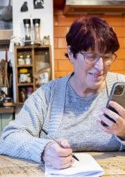woman using her phone and writing at home