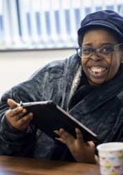 Woman smiling and holding an ipad.