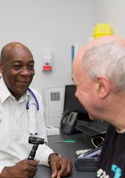 GP sitting opposite a patient about to take their tempreature