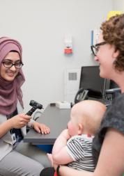 Female GP talking to female patient with baby