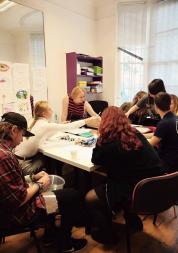 Young people round a table talking and working