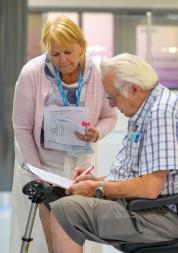 Man in a wheelchair with a lady standing next to him