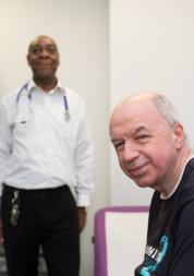 GP Surgery, Man in focus, in foreground to right, Doctor blurred, in background to left