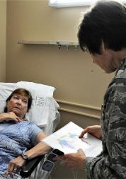 Female patient in hospital bed, doctor facing patient with clipboard